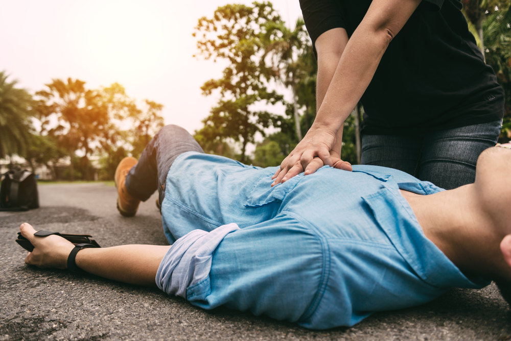 man doing first aid to an injured lying on the street