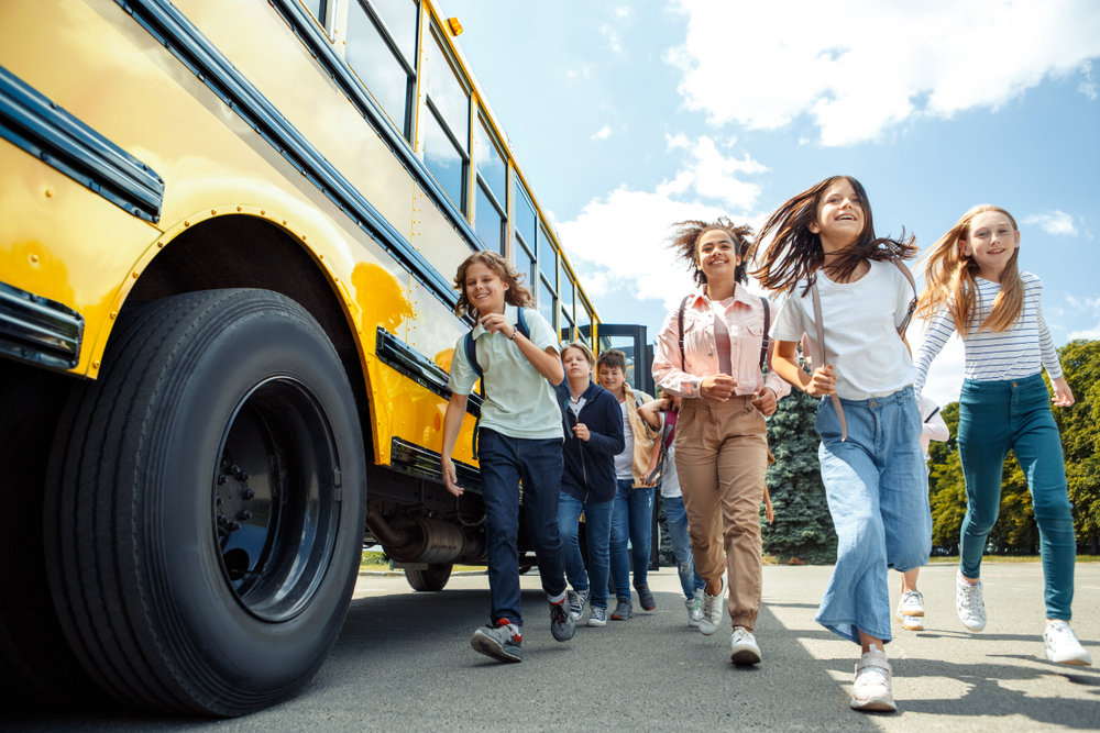 group of children classmates running from school bus