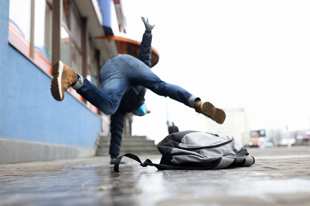 man in winter dress slip on sidewalk with ice closeup background