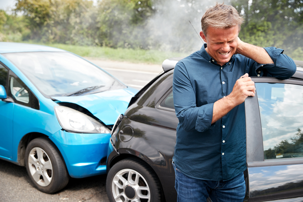 Mature Male Motorist With Whiplash Injury In Car Crash Getting Out Of Vehicle