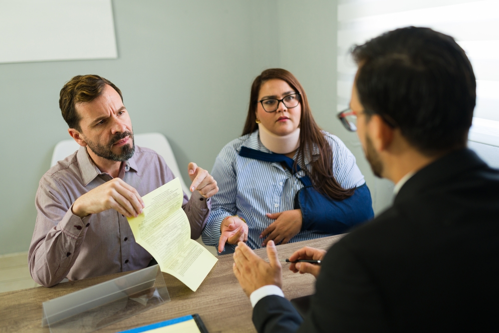 Injured woman and man at desk, discussing difficult insurance claim with a lawyer for accident compensation