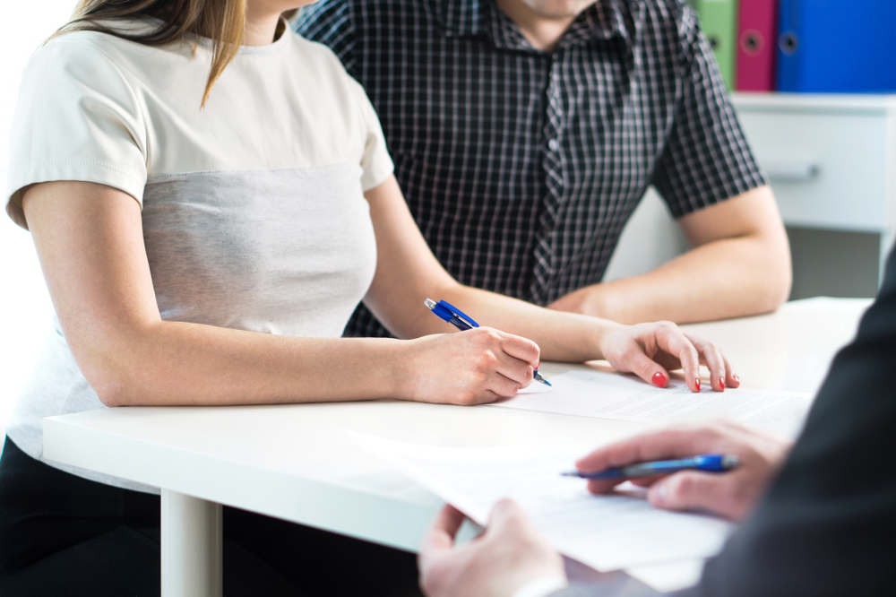 Man and woman having meeting with banker in bank or lawyer in office.